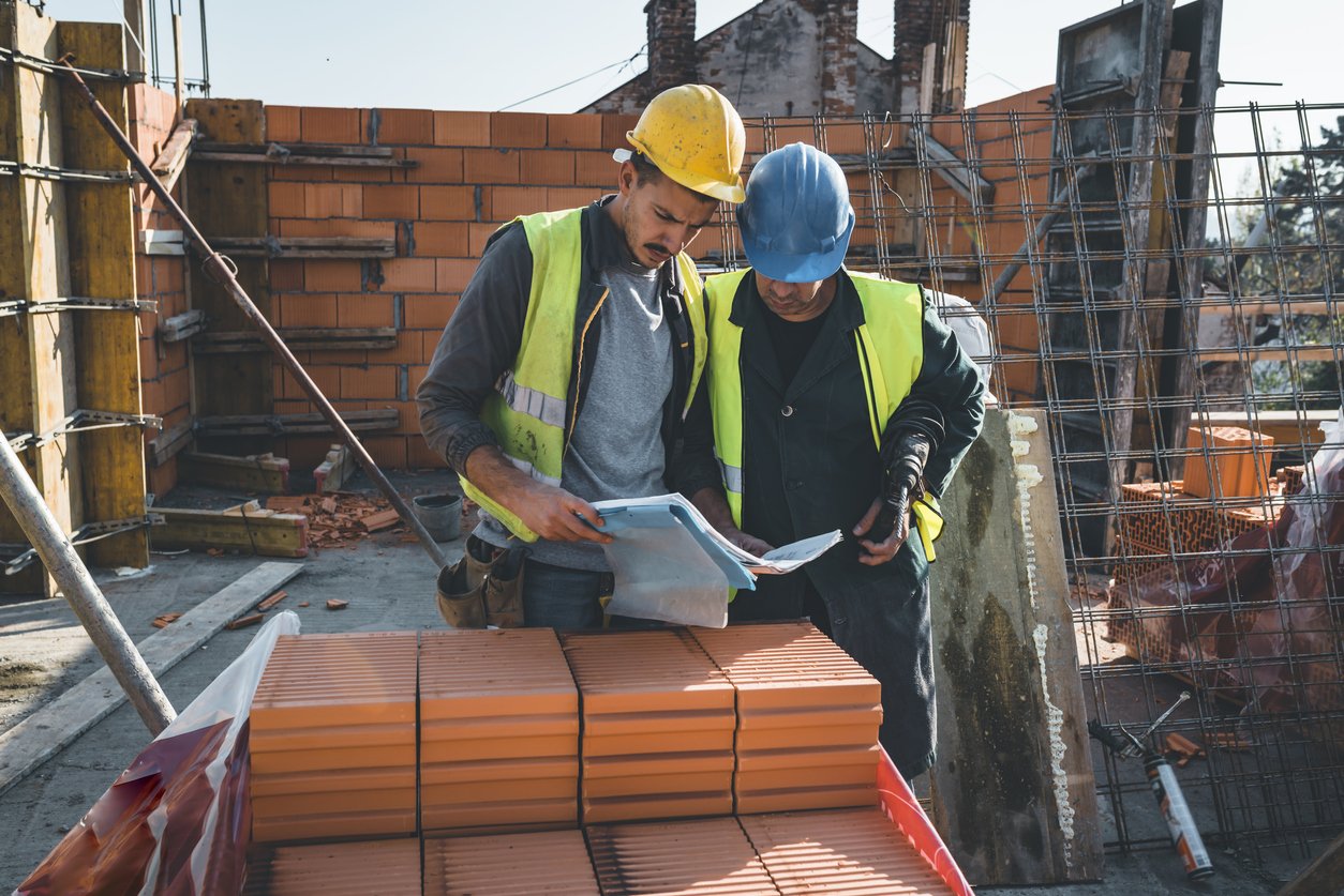 Experienced Construction Worker is Explaining Building Project to his Coworker