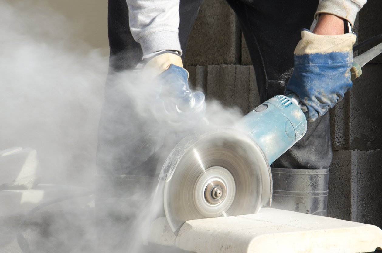 Worker cutting stone with an electric grinder