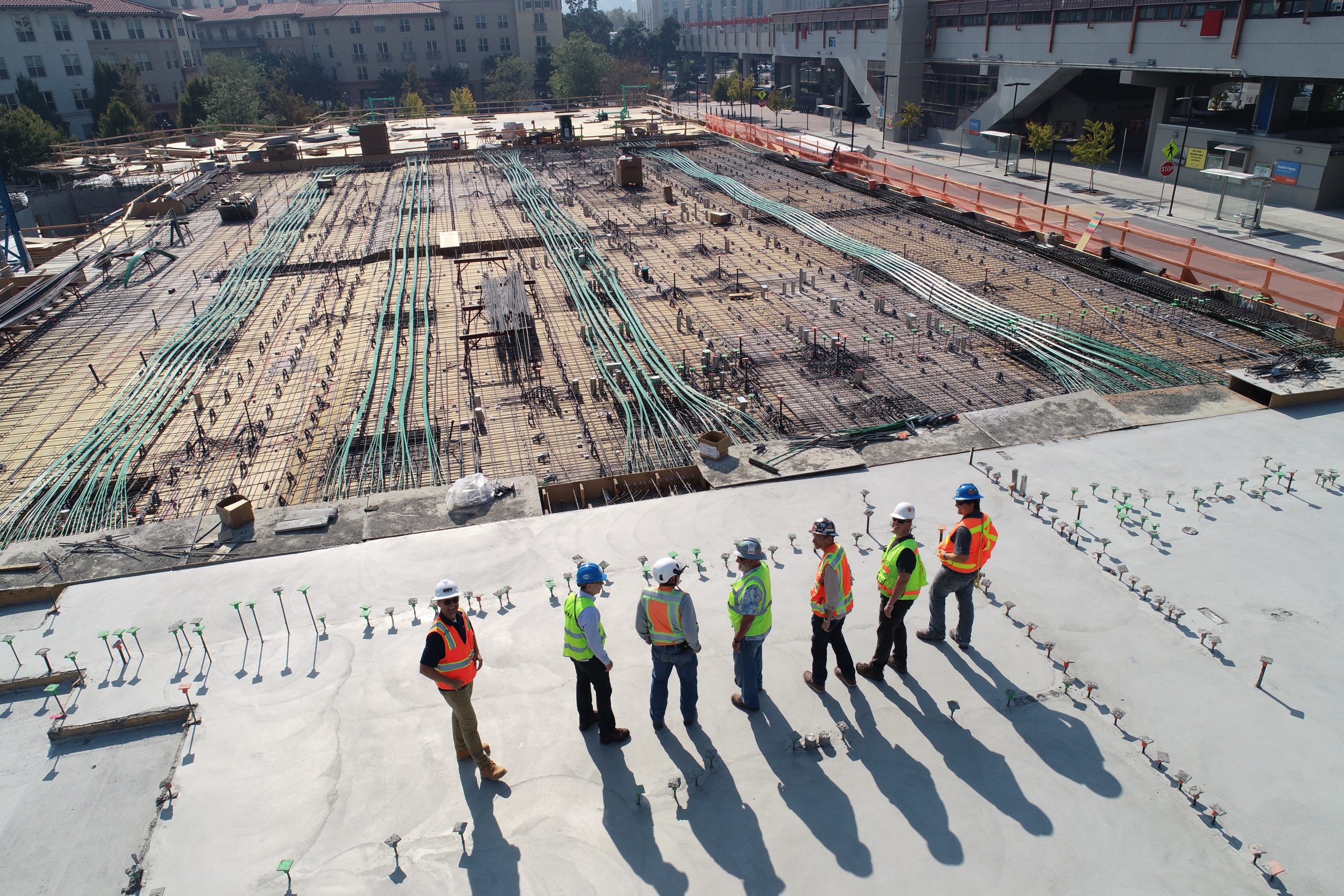 group of workmen looking out over building foundations with cabling and pipes