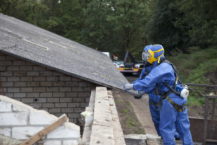 Man clearing asbestos from old roof / Hazardous substances