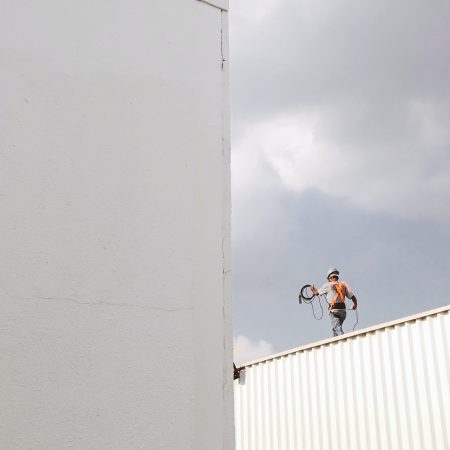 man-walking-on-roof-top-2317640 Worker walking on roof top carrying wire